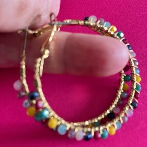 Ladies hoop earrings, gold with colorful shiny beads all around the hoops.